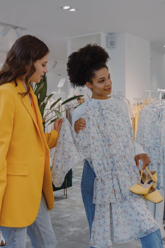 Services Two women shopping for stylish clothing in a modern fashion boutique.