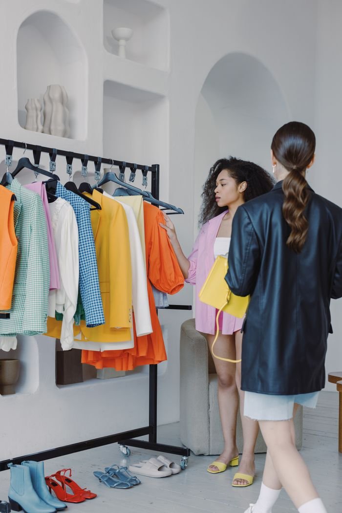 Mastering the First Impression: Your intriguing post title goes here Fashion stylists coordinating outfits in a chic boutique with vibrant apparel selection.